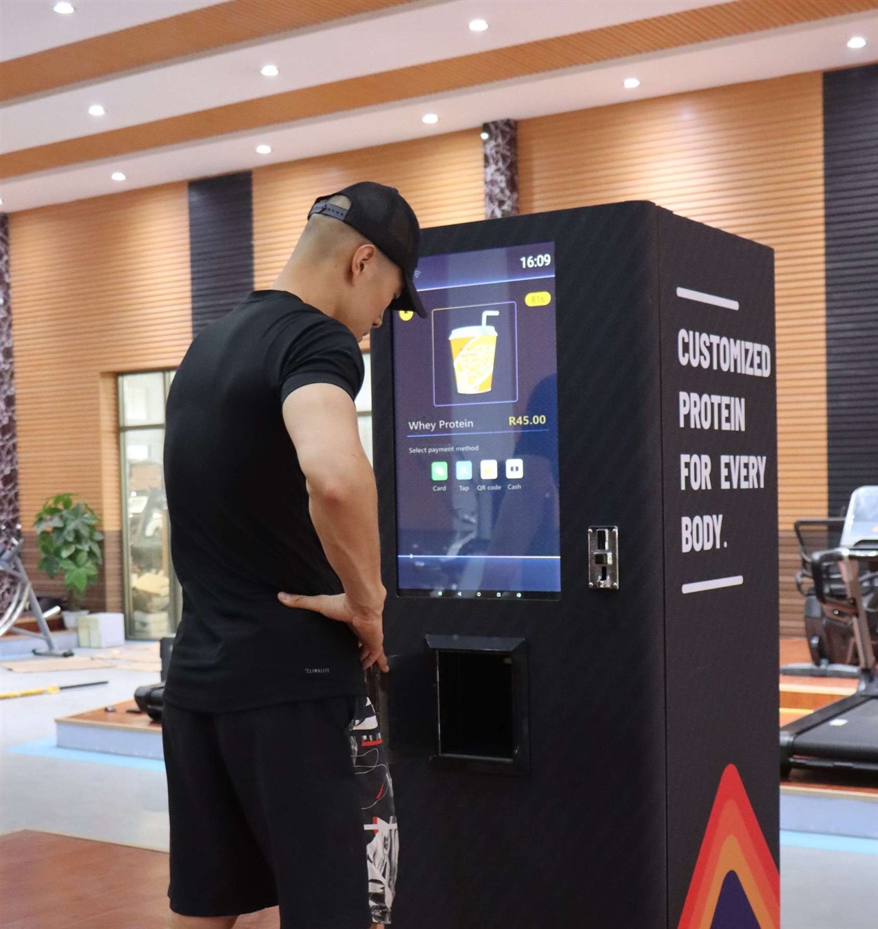 A man choosing a whey protein shake on the Nutrition 7 touch screen in a gym